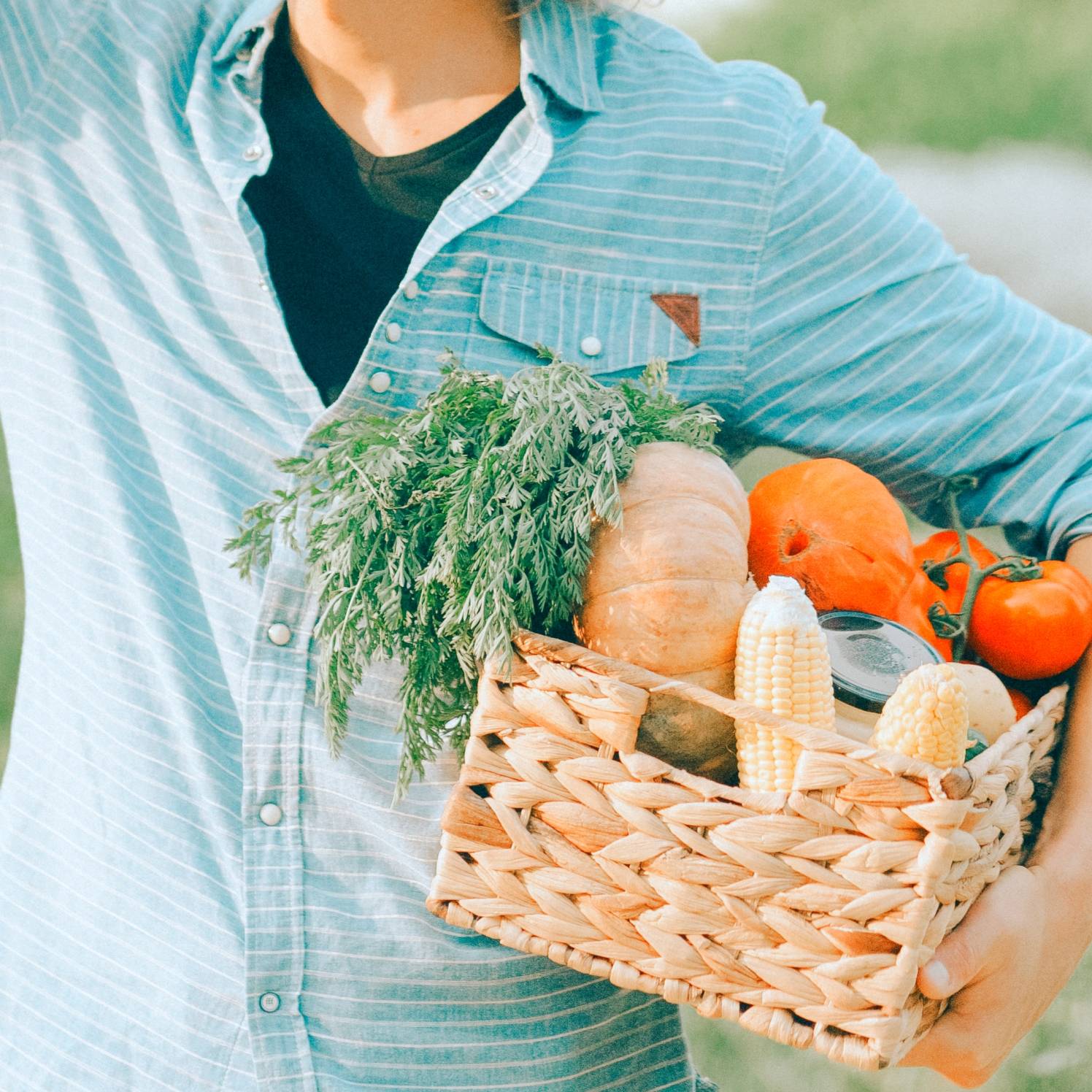 Homem de camisa azul segurando uma cesta com produtos agrícolas